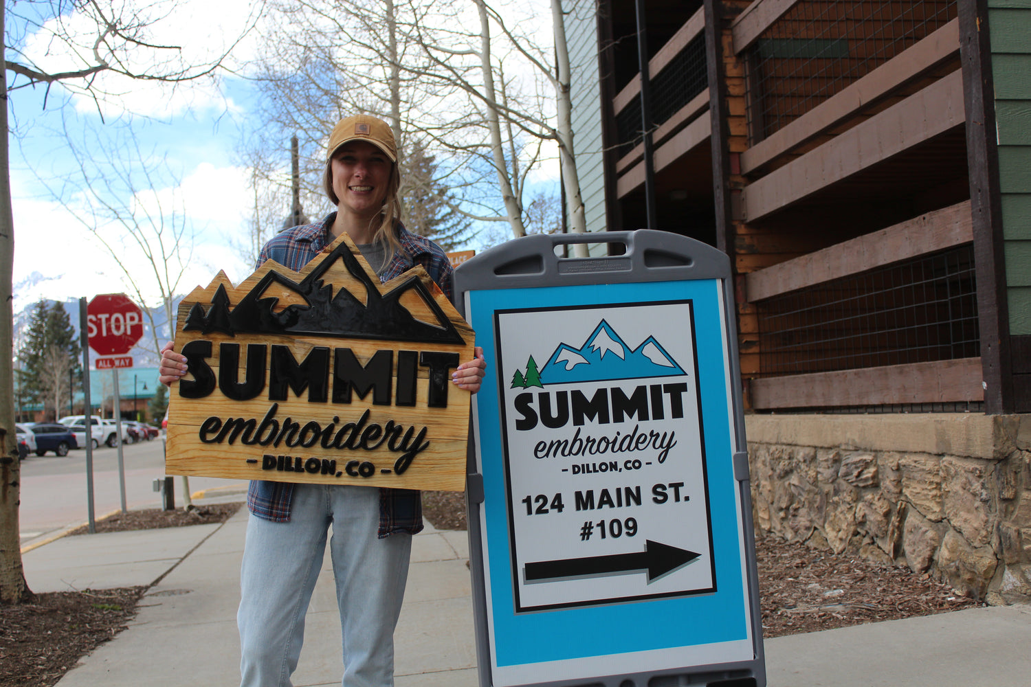 Company owner holding their new Outdoor Wood Signage for company Summit Embroidery made by Elevated Engravings.
