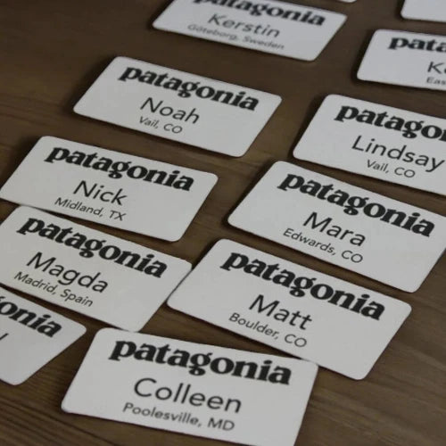 White square employee nametags engraved in black for Patagonia.