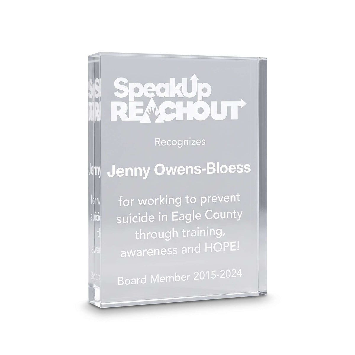 A clear acrylic award plaque featuring engraved white text that reads 'SpeakUp REACHOUT' and recognizes Jenny Owens-Bloess, with additional text below on a clean white background.