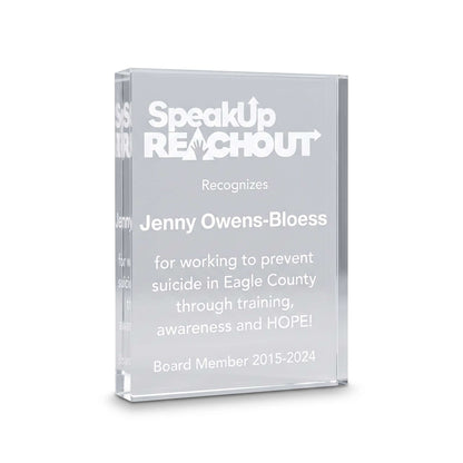 A clear acrylic award plaque featuring engraved white text that reads 'SpeakUp REACHOUT' and recognizes Jenny Owens-Bloess, with additional text below on a clean white background.