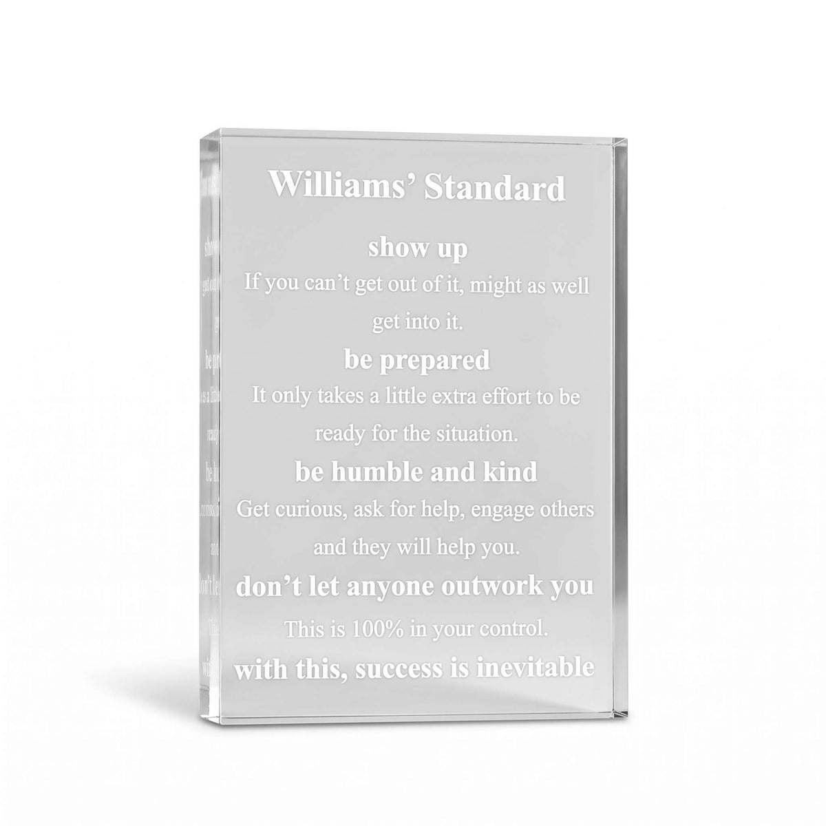 A clear acrylic or glass standee with engraved white text reading 'Williams' Standard' and a motivational quote, shown on a clean white background.