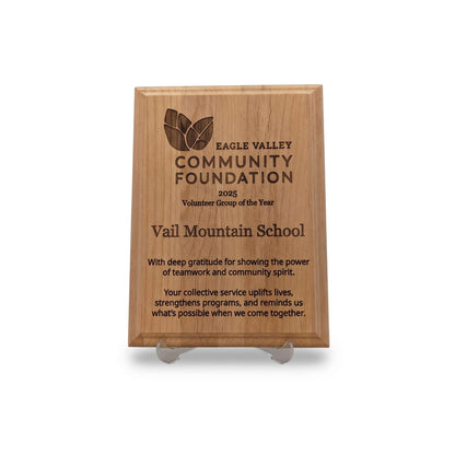A rectangular engraved wooden plaque on a clear acrylic display stand, featuring the Eagle Valley Community Foundation 2005 Volunteer Group of the Year award for Vail Mountain School.