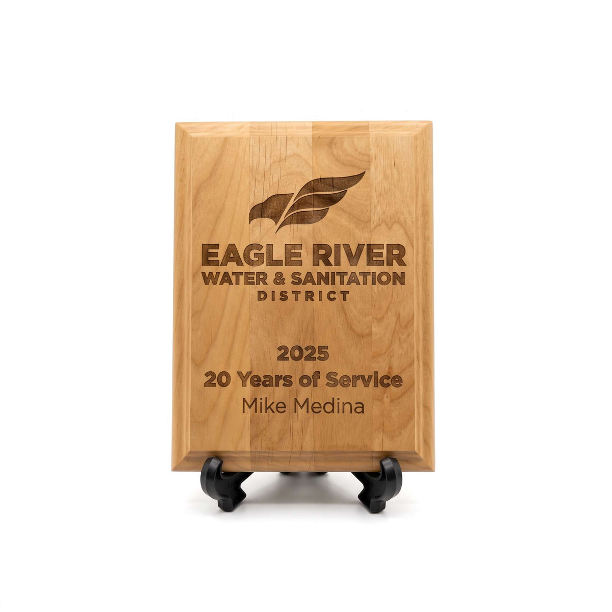 A rectangular wooden plaque on a small black display stand, engraved with the Eagle River Water & Sanitation District logo and the text '2025 20 Years of Service Mike Medina' on a white background.