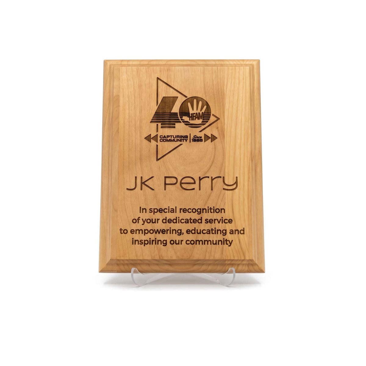 A personalized wooden plaque on a clear acrylic display stand, featuring a custom engraved logo and text for 'JK Perry'  in recognition of his service and impact on community. on a clean white background.