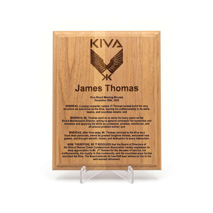 A rectangular wooden engraved plaque on a clear acrylic stand, featuring the Kiva logo and personalized text for James Thomas. In recognition of his years of service to the property.