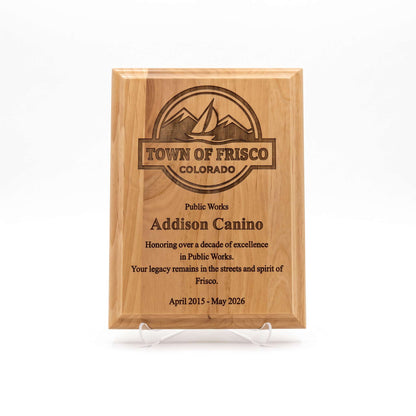 A rectangular wooden plaque on clear acrylic display stands, engraved with the Town of Frisco Colorado logo and personalized text recognition for Addison Canino for her years of service, shown against a plain white background.