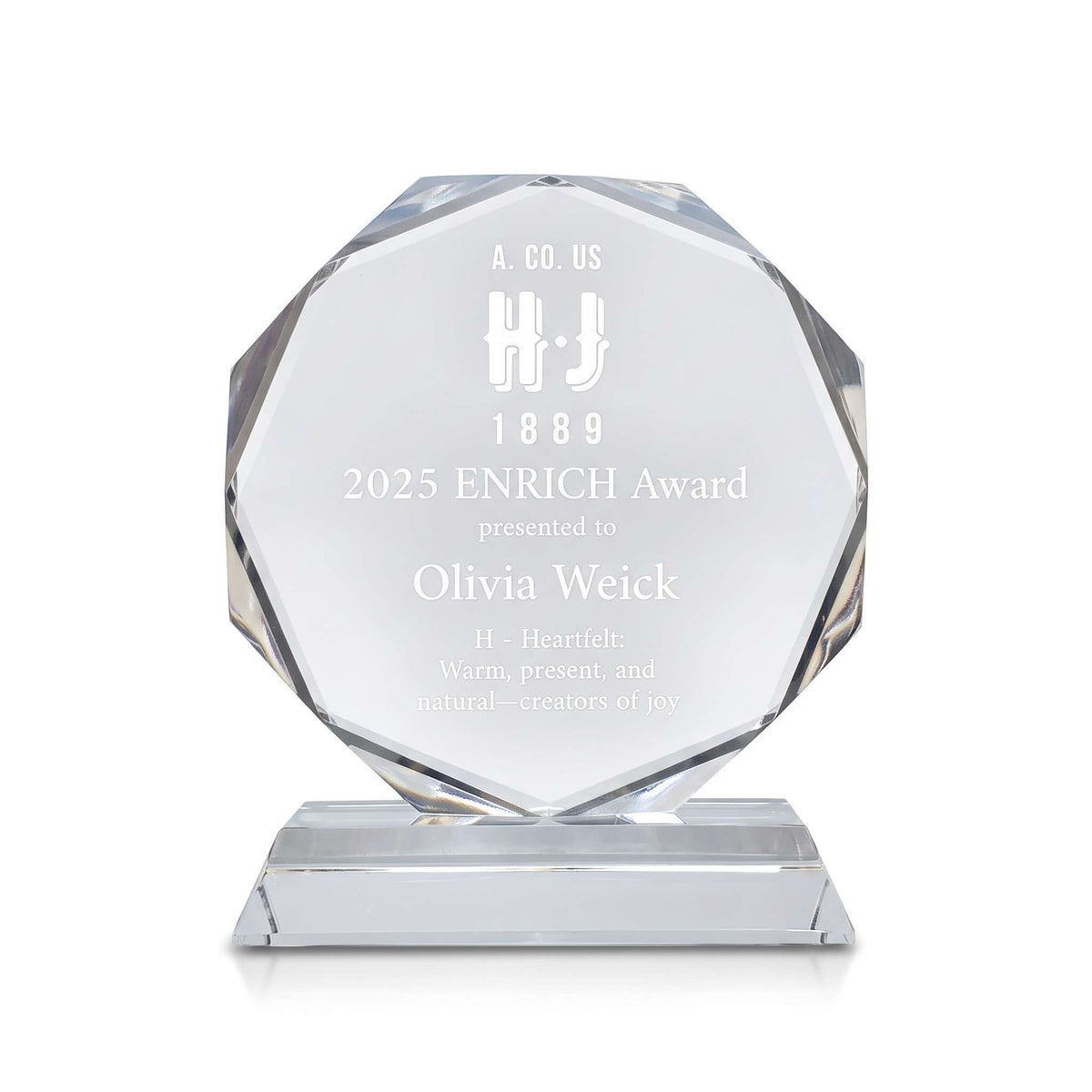 A faceted clear crystal award plaque on a rectangular base, engraved with the text '2025 ENRICH Award presented to Olivia Weick' and a logo, shown on a white background.