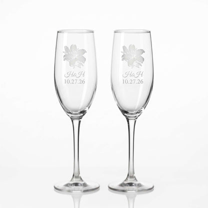 Two glass champagne flutes custom engraved for wedding. Engraved flower, initials of bride and groom, and the date of their wedding.