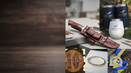A collage showing branded Eagle River products: a brown leather knife sheath with a knife, two dark insulated tumblers, a white insulated tumbler, a wooden engraved plaque, a gold ring, and a blue/yellow engraved ribbon award, alongside a large dark wood background panel.